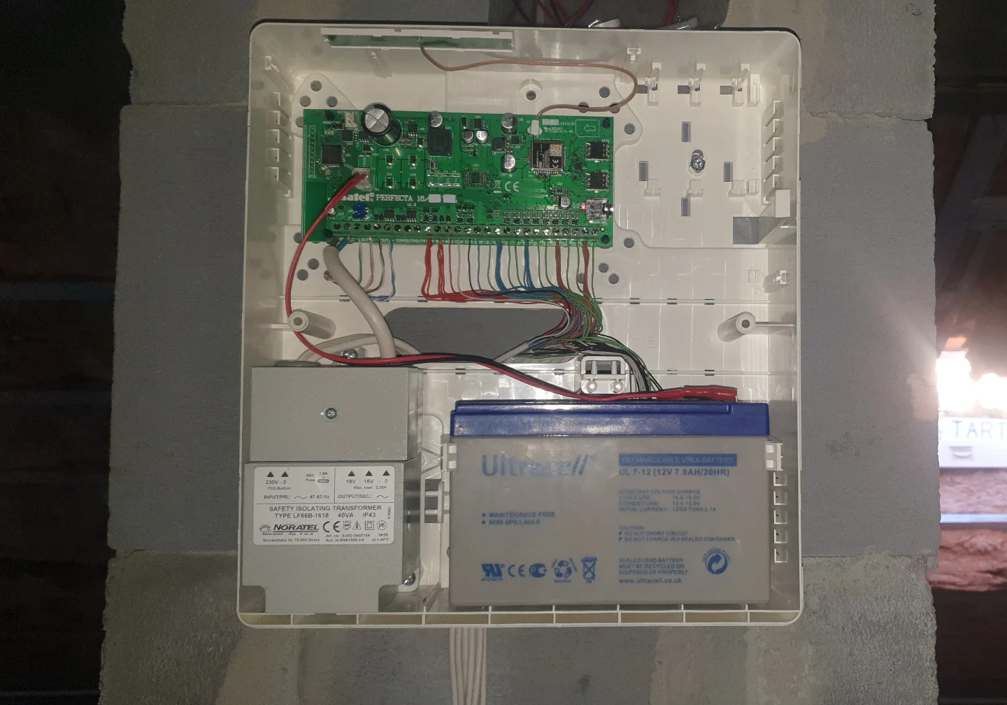 Wnętrze centrali alarmowej Satel Perfecta z akumulatorem Ultracell i transformatorem Noratel – profesjonalny montaż w puszce przez Winkam Rybnik.