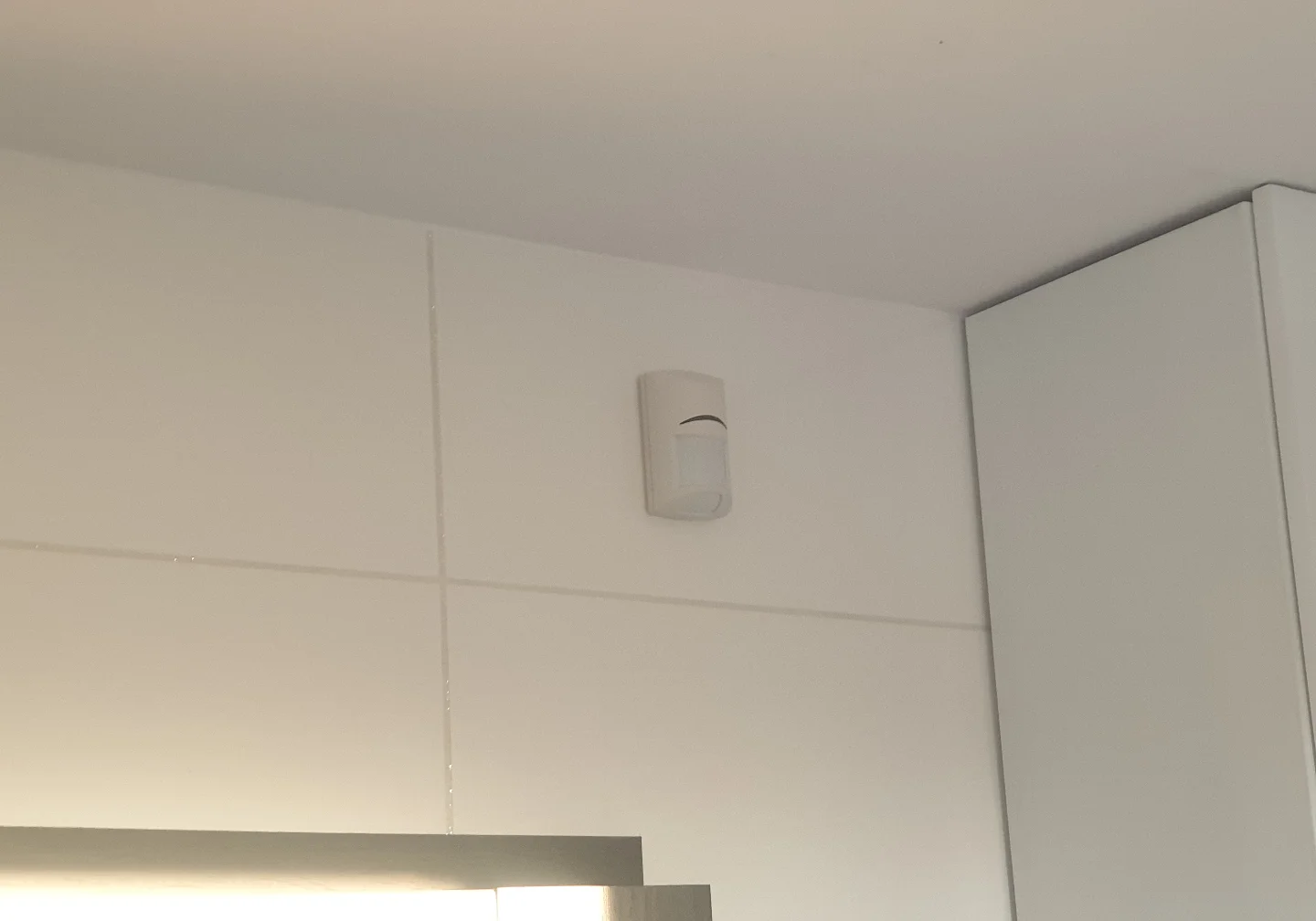 Dyskretny montaż czujnika ruchu Bosch na białych płytkach w łazience – profesjonalna instalacja alarmowa Winkam Rybnik.